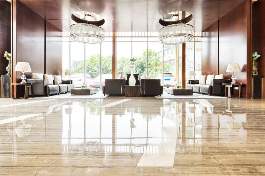 Modern hotel lobby with polished marble floors, sofas and large windows reflecting daylight